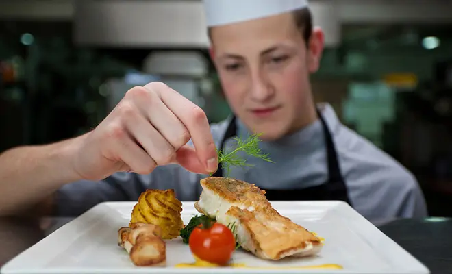 Ein erfahrener Koch in professioneller Küche bereitet Speisen zu